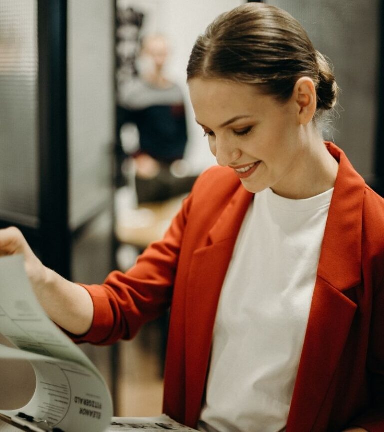 Woman in red blazer and white shirt holding clipboard